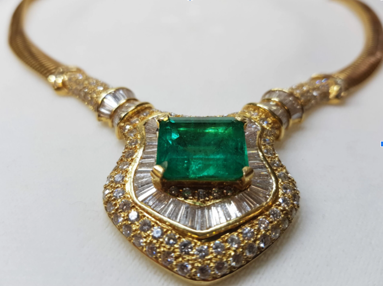 A gold necklace, embellished with diamonds and with an impressive emerald mounted at its centre.