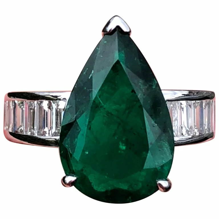A pear emerald mounted on top of a diamond ring.
