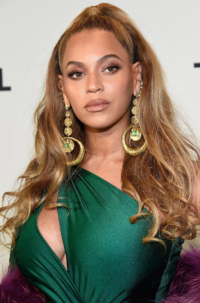Beyonce wearing a set of gold and emerald earrings