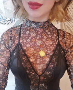 Person wearing a floral top, black lace camisole, and a gold necklace.