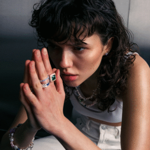 Person wearing jewelry, hands clasped, looking to the side.
