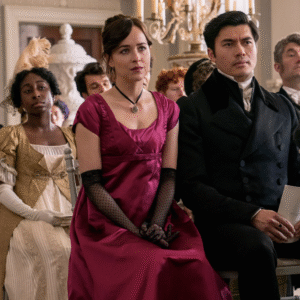 People in period clothing sit in rows, looking forward.
