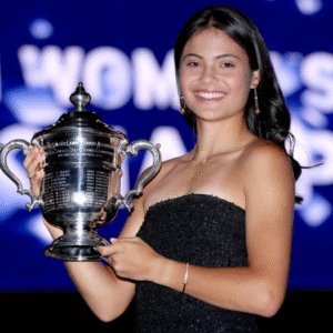 Person in strapless dress holds a large silver trophy and smiles.