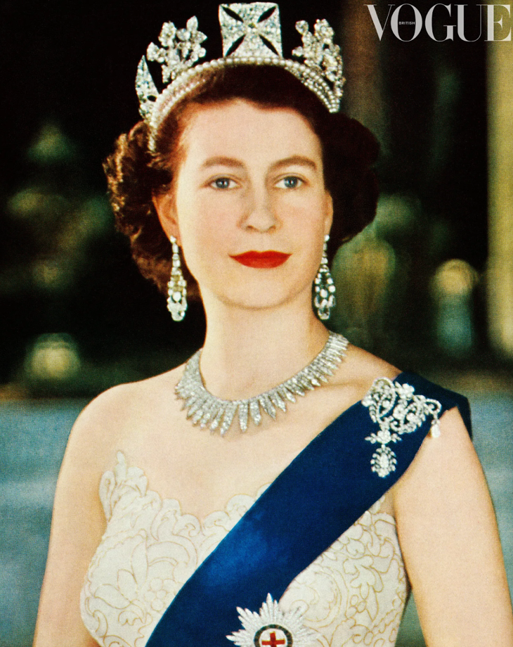 Person in gown, tiara, and jewelry with a blue sash. Vogue logo in the upper right corner.