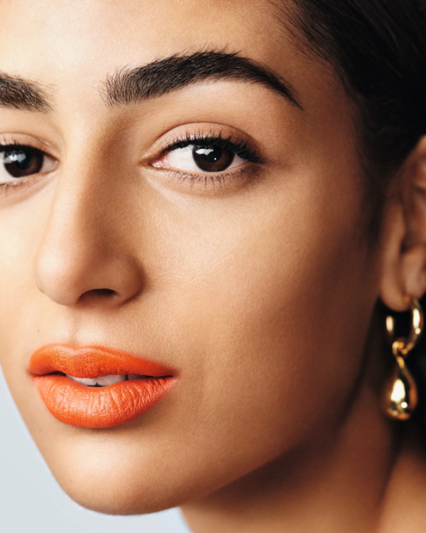 Person with orange lipstick and gold earrings.