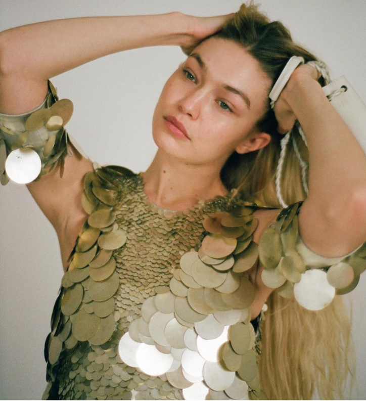 Person in sequined top holds hair up.