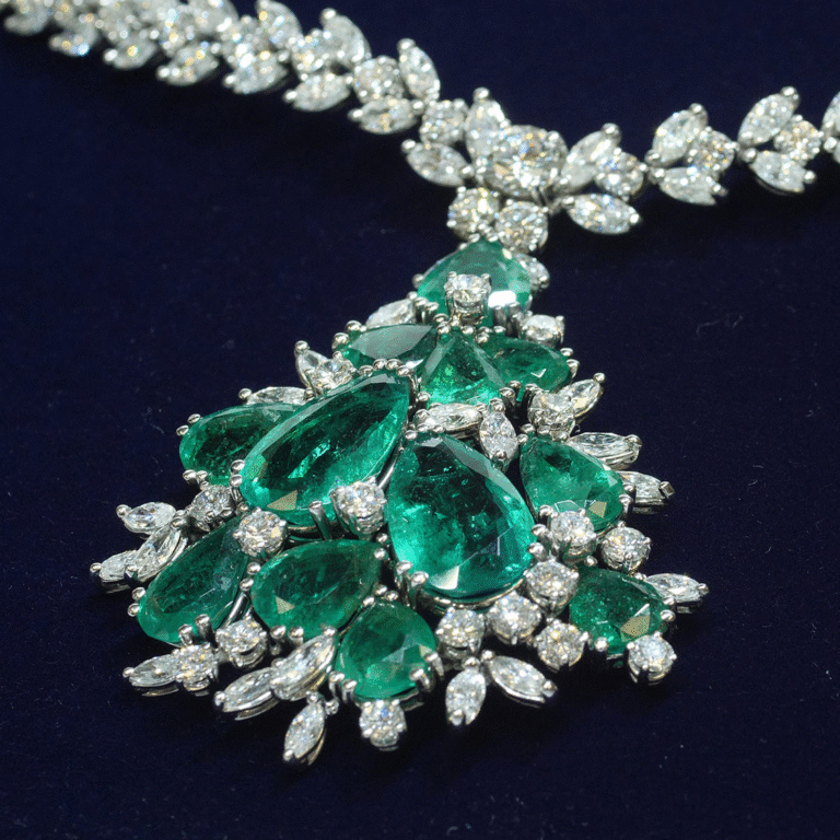 Necklace with white diamonds and pear-shaped green emeralds on a dark blue background.