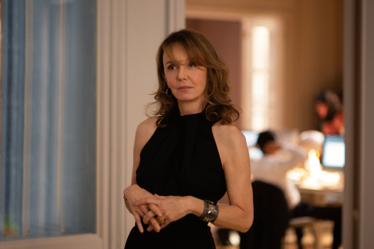 Person in black halter dress stands with hands clasped. Other people are in the background.